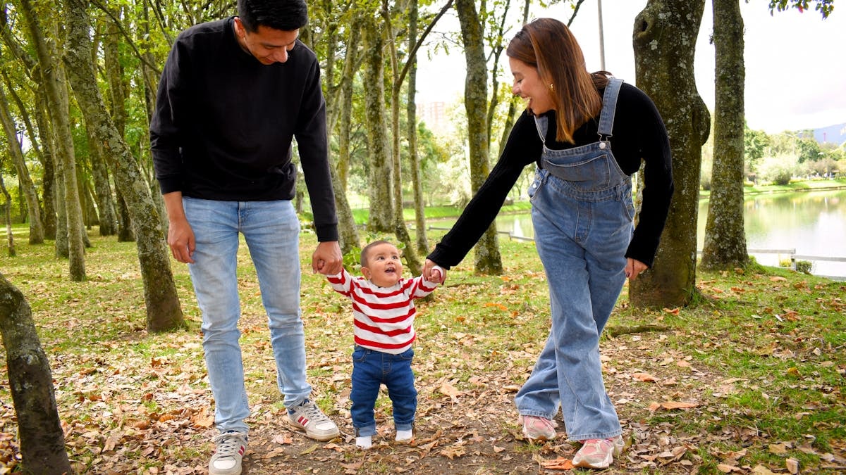 A joyful family enjoys a walk under lush green trees in the park.